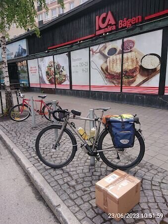 Fahrrad vor Supermarkt, ein Paket steht vor dem Rad